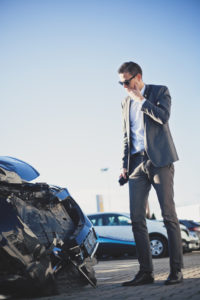 businessman checking out the damage to his car